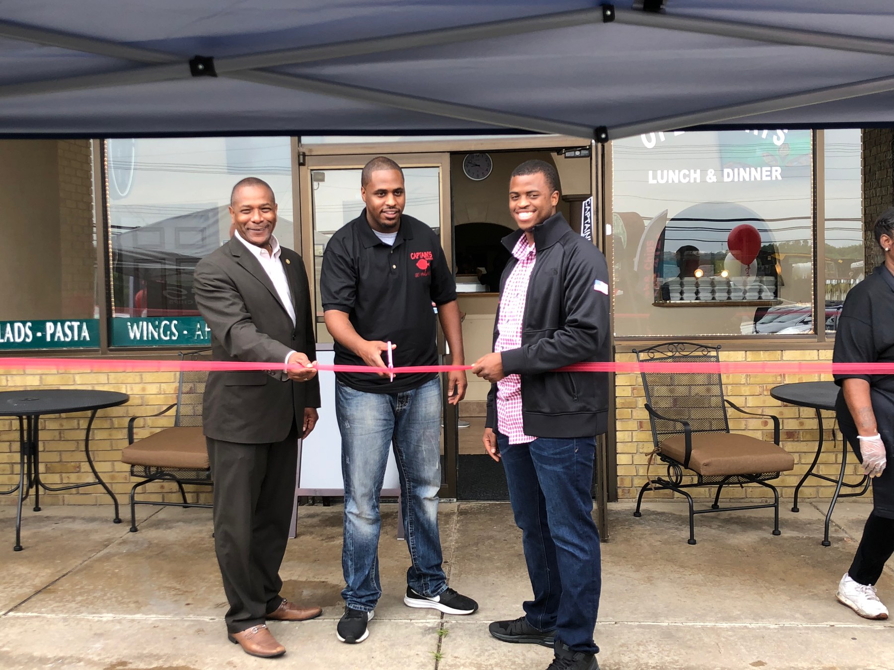 Participants gathered for a ribbon-cutting outside a local business